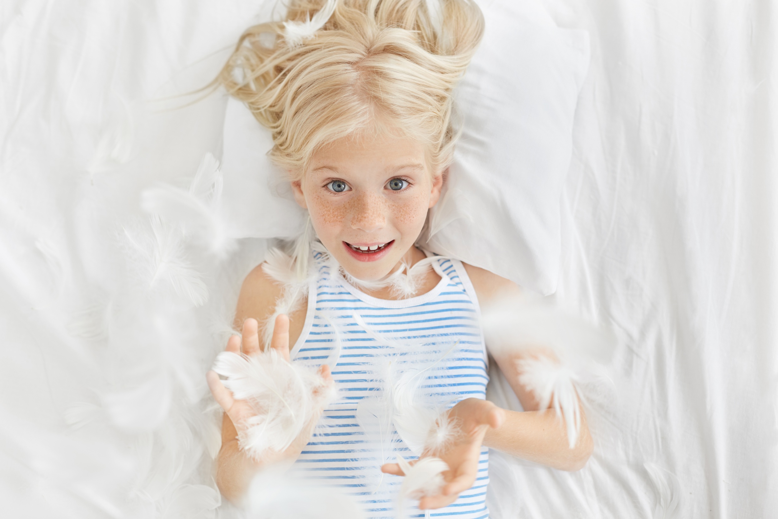 2 happy-childhood-concept-leisure-fun-relaxation-top-picture-adorable-blonde-freckled-little-girl-preschooler-looking-through-flying-feathers-after-pillow-fighting-her-room.jpg