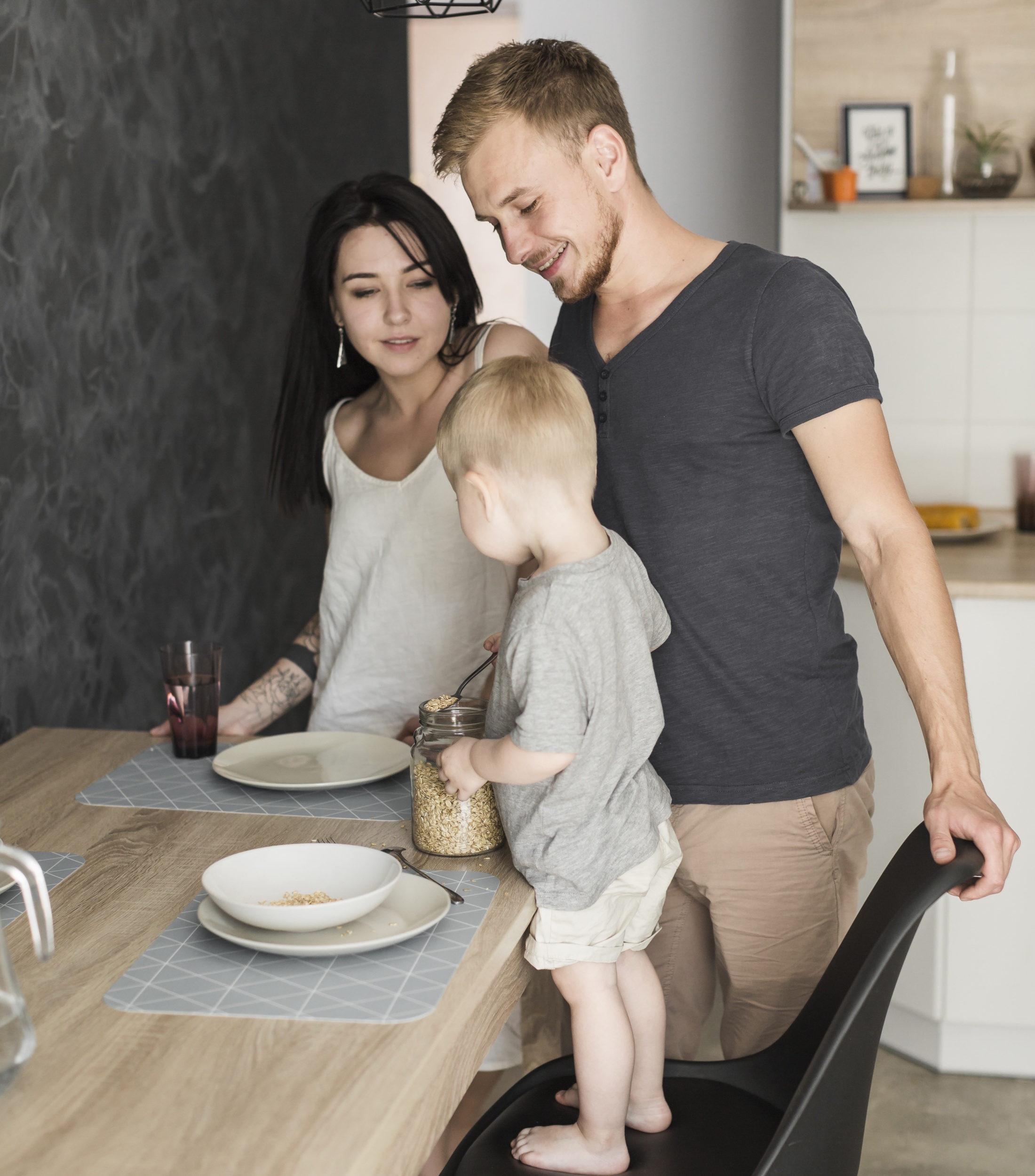 3 smiling-young-couple-looking-little-boy-standing-chair-serving-oats-plate-breakfast.jpg