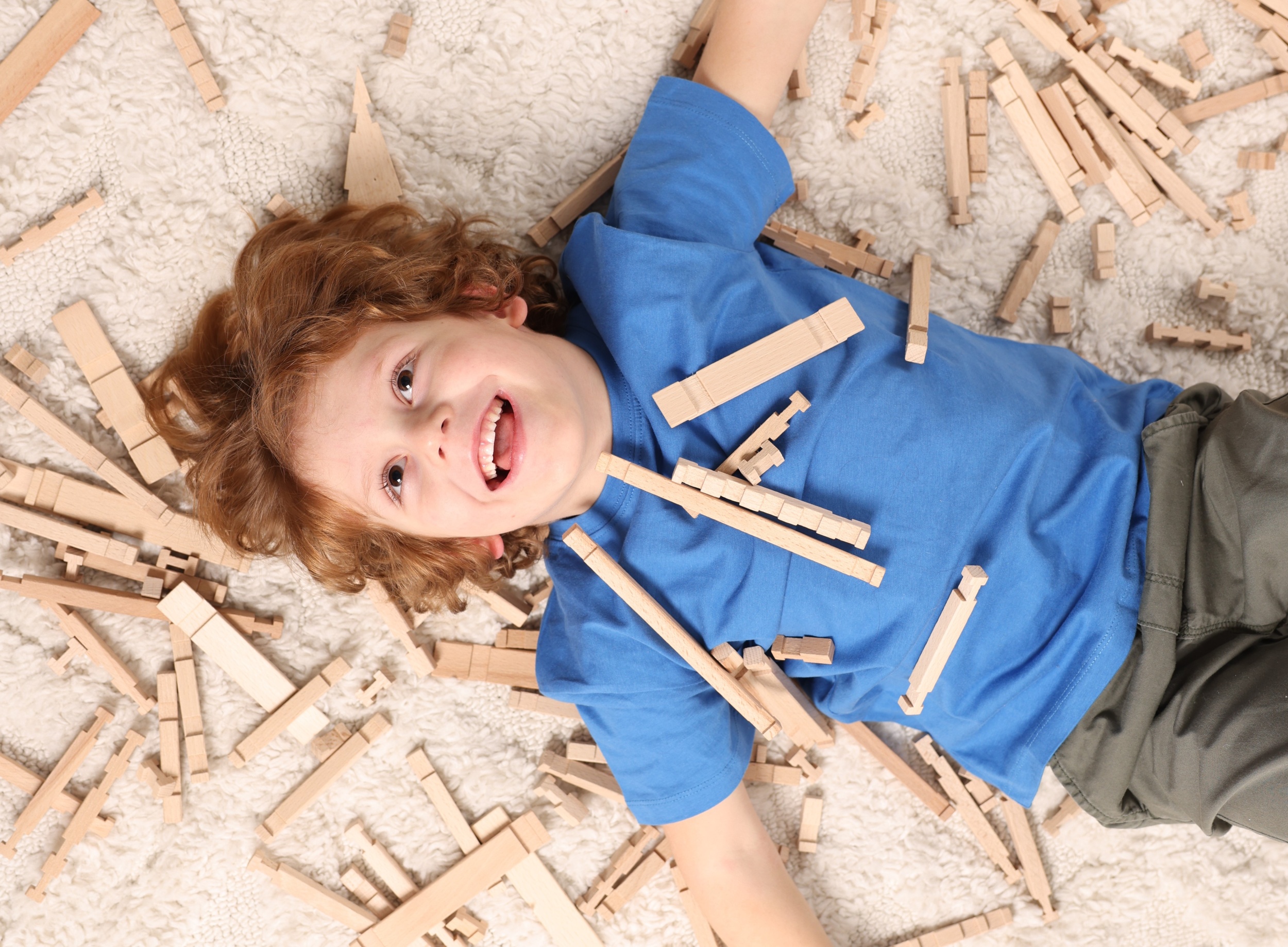 9 cute-little-boy-surrounded-by-wooden-construction-set-carpet-home-top-view-childs-toy.jpg