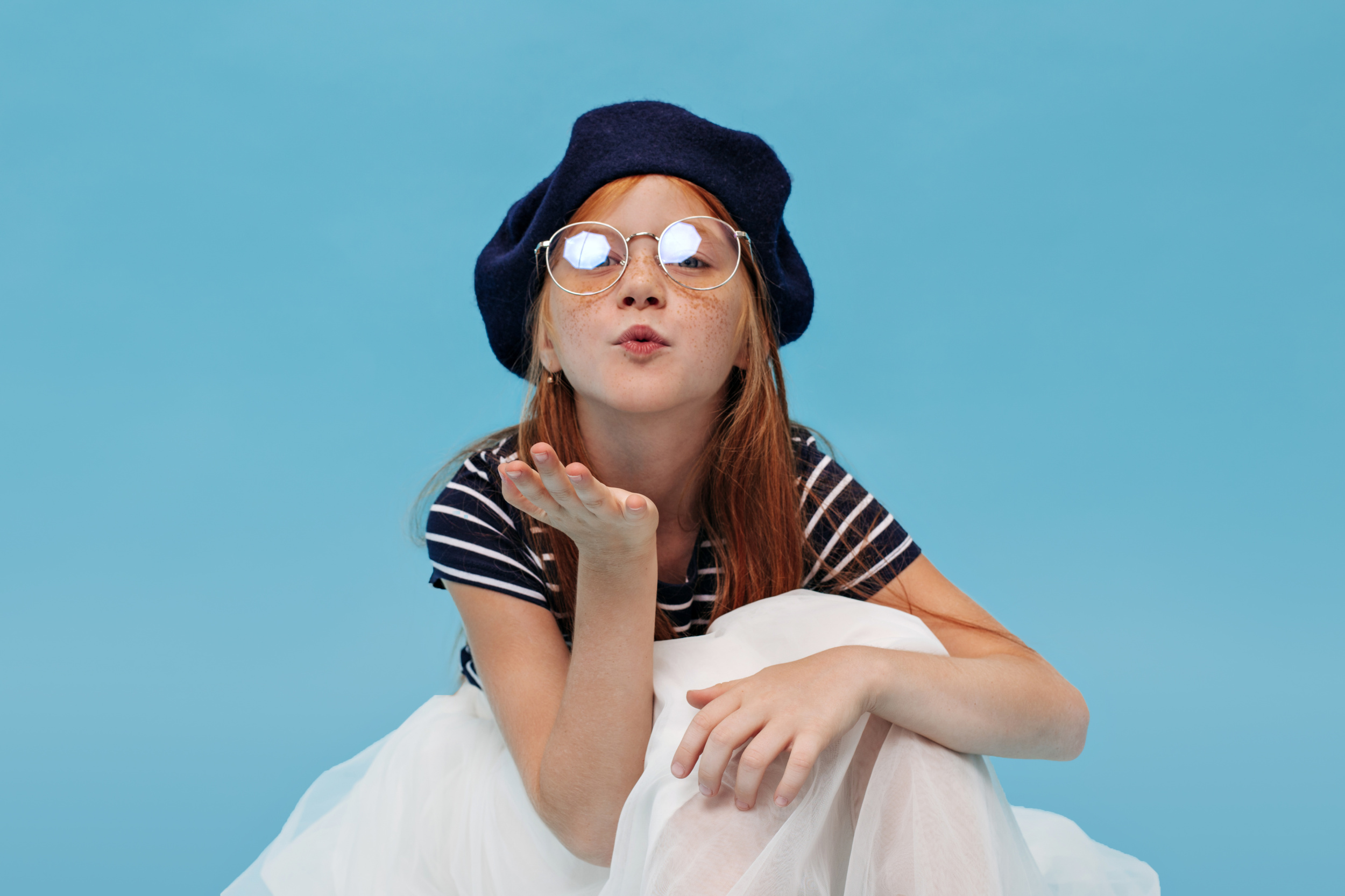 beautiful-ginger-girl-dark-hat-striped-cool-tshirt-blowing-kiss-looking-into-camera-isolated-blue-background.jpg