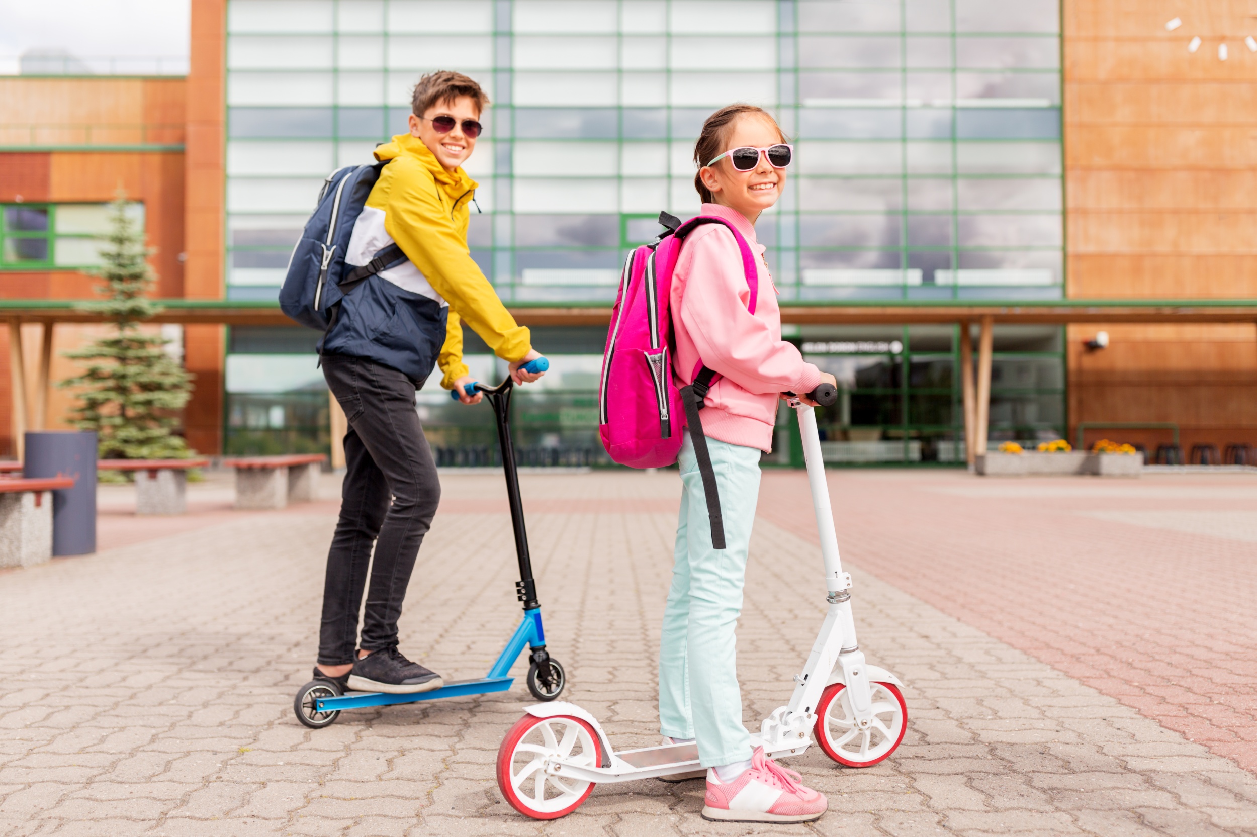 3 school-children-with-backpacks-riding-scooters.jpg