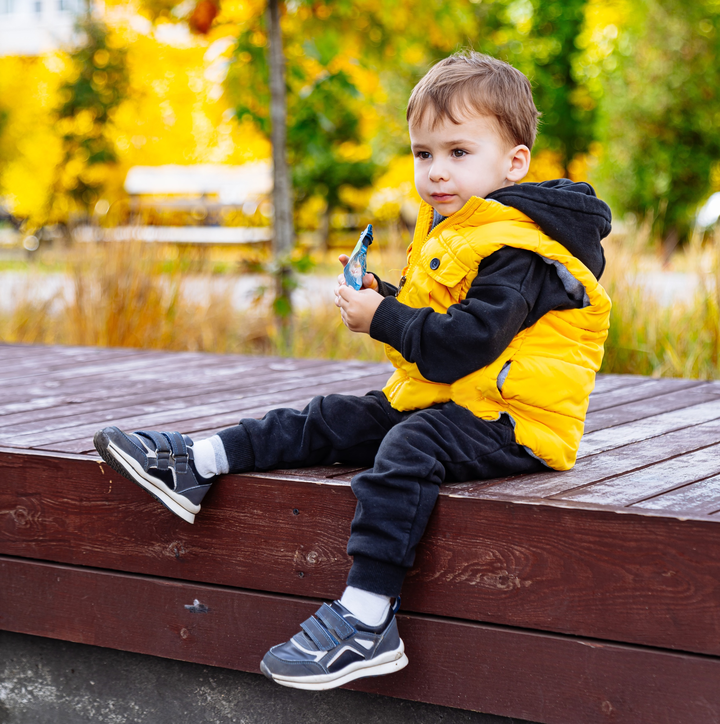 3 little-boy-sits-wooden-bench-yellow-jacket-black-pants-holds-toy-car-his-hands.jpg