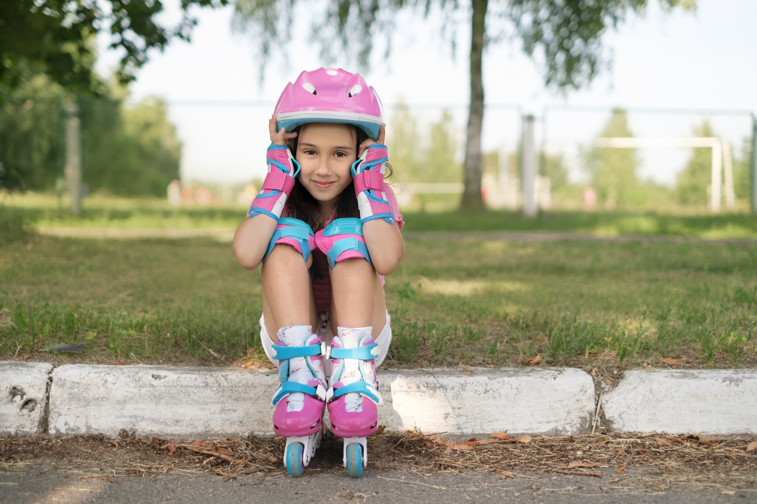 1 girl-pink-helmet-roller-skates-is-sitting-side-sidewalk.jpg