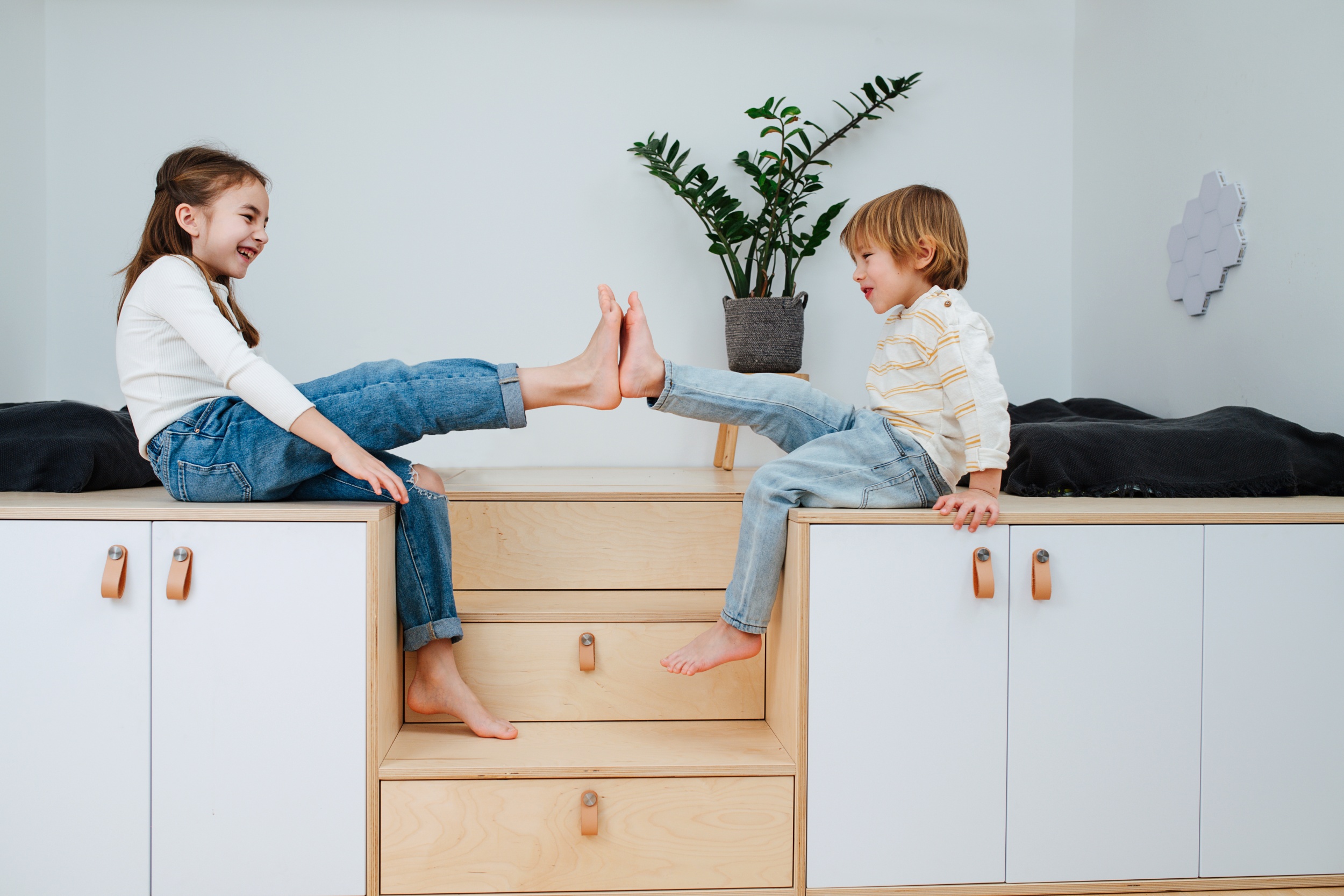 1 cheerful-siblings-sitting-wooden-elevation-front-each-other-presing-bare-feet-fun-side-view.jpg