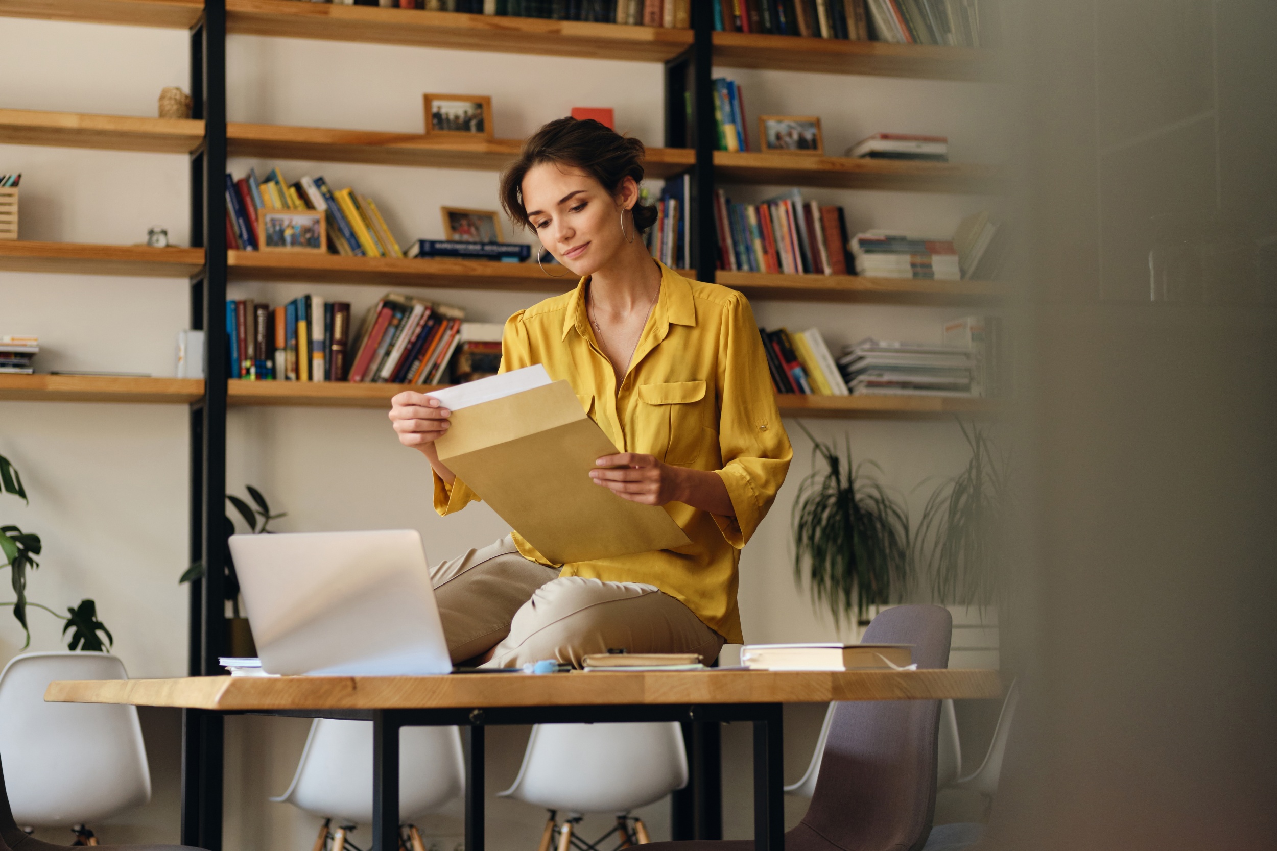 young-pretty-smiling-woman-yellow-shirt-sitting-desk-with-papers-laptop-while-dreamily-working-modern-office.jpg