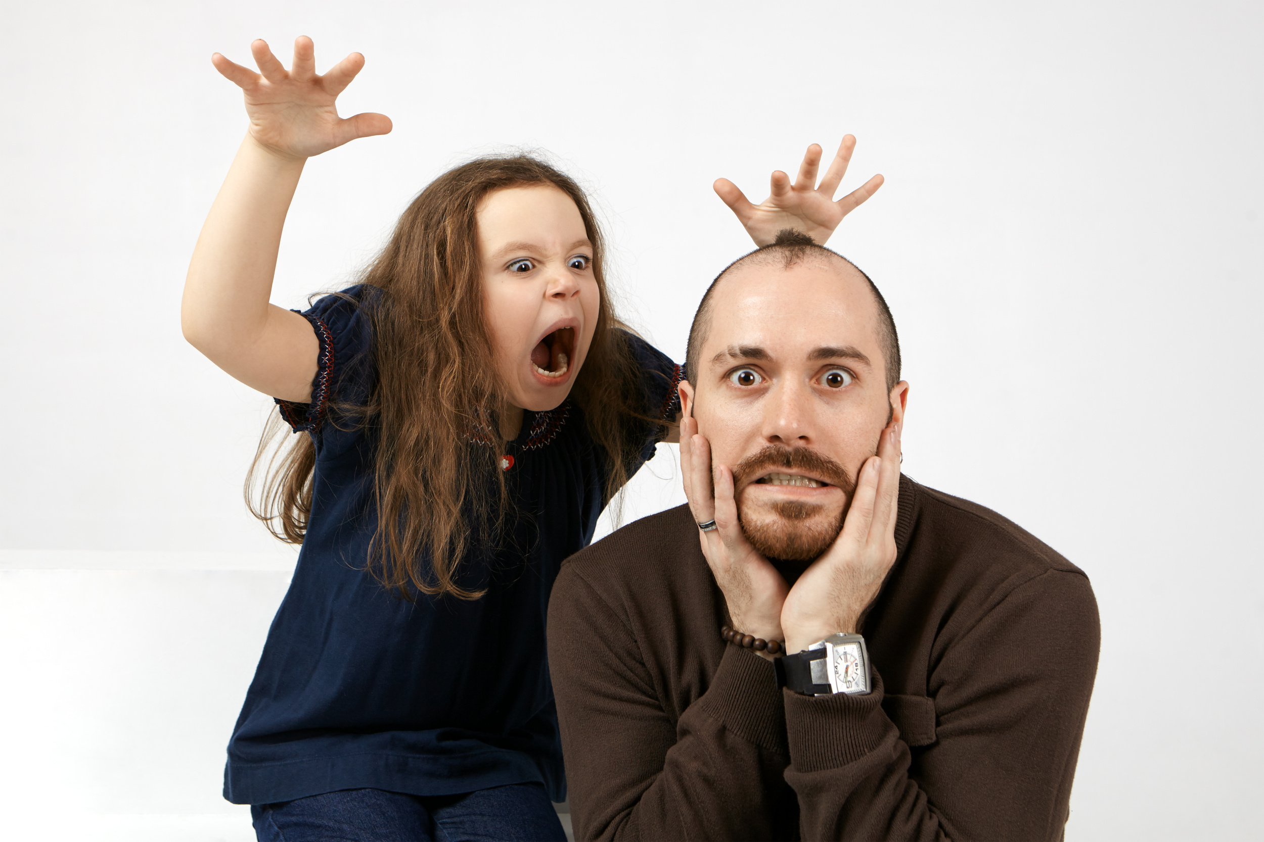portrait-of-funny-young-bearded-male-keeping-hands-on-his-face-being-terrified-by-his-little-daughter-who-standing-behind-him-shouting.jpg