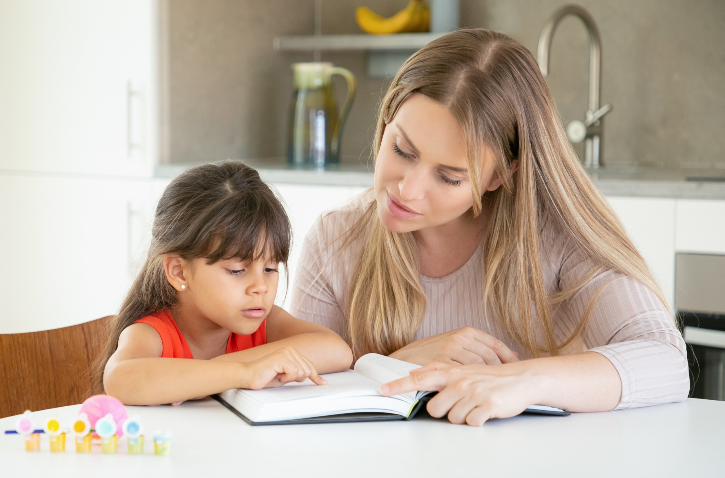 pretty-mom-reading-book-with-daughter-kitchen.jpg