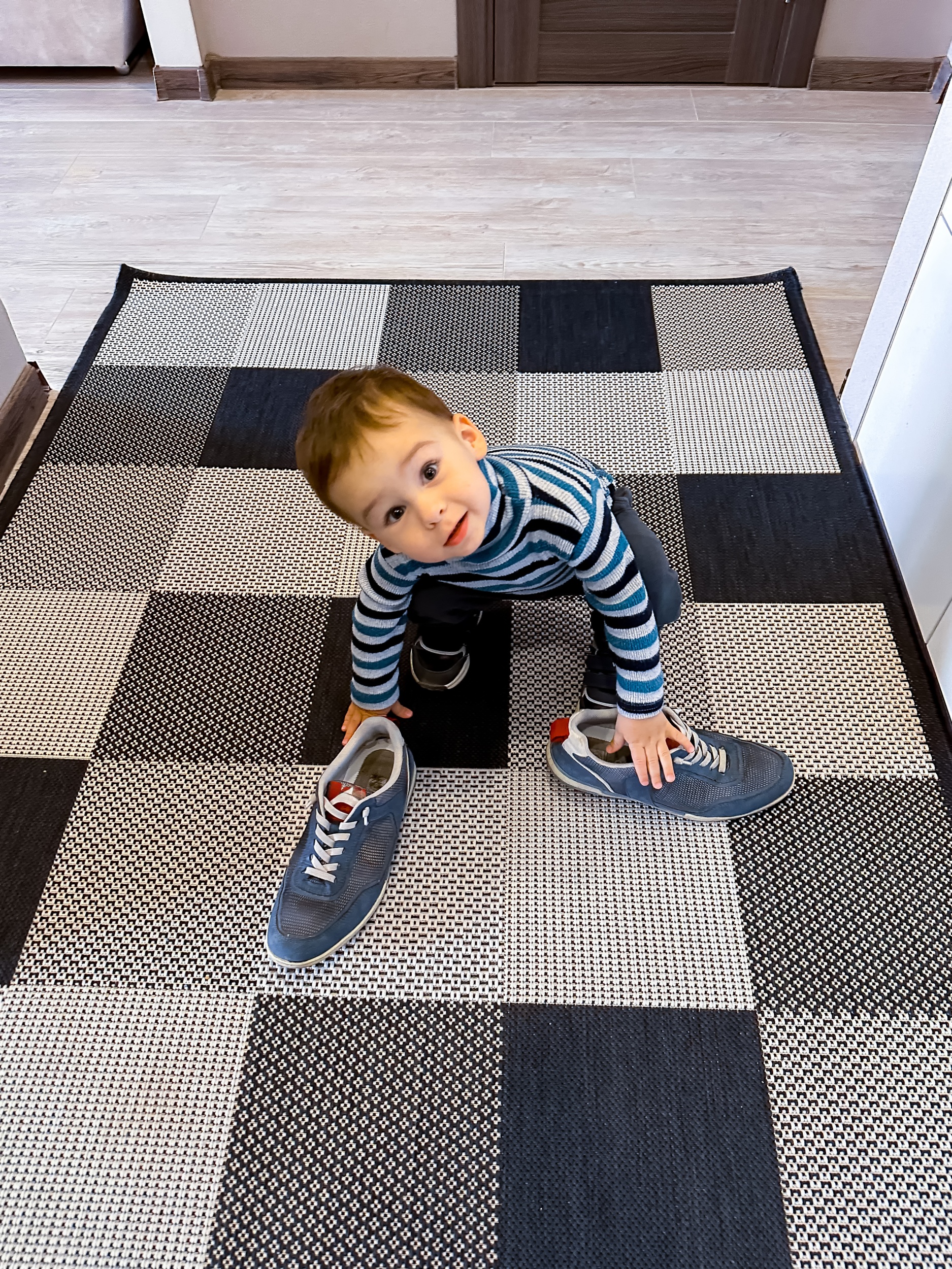 80 - molodoi-mal-cik-stoit-na-sahmatnom-kovre-s-nogami-v-dvuh-sinih-botinkah.jpg