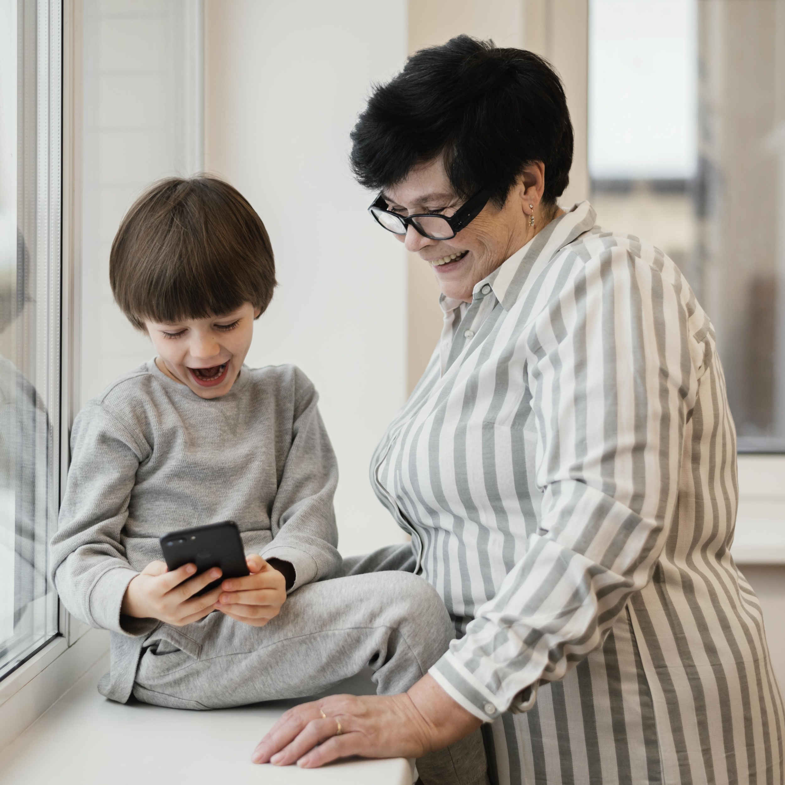 2 smiley-grandmother-watching-grandson-playing-with-smartphone.jpg