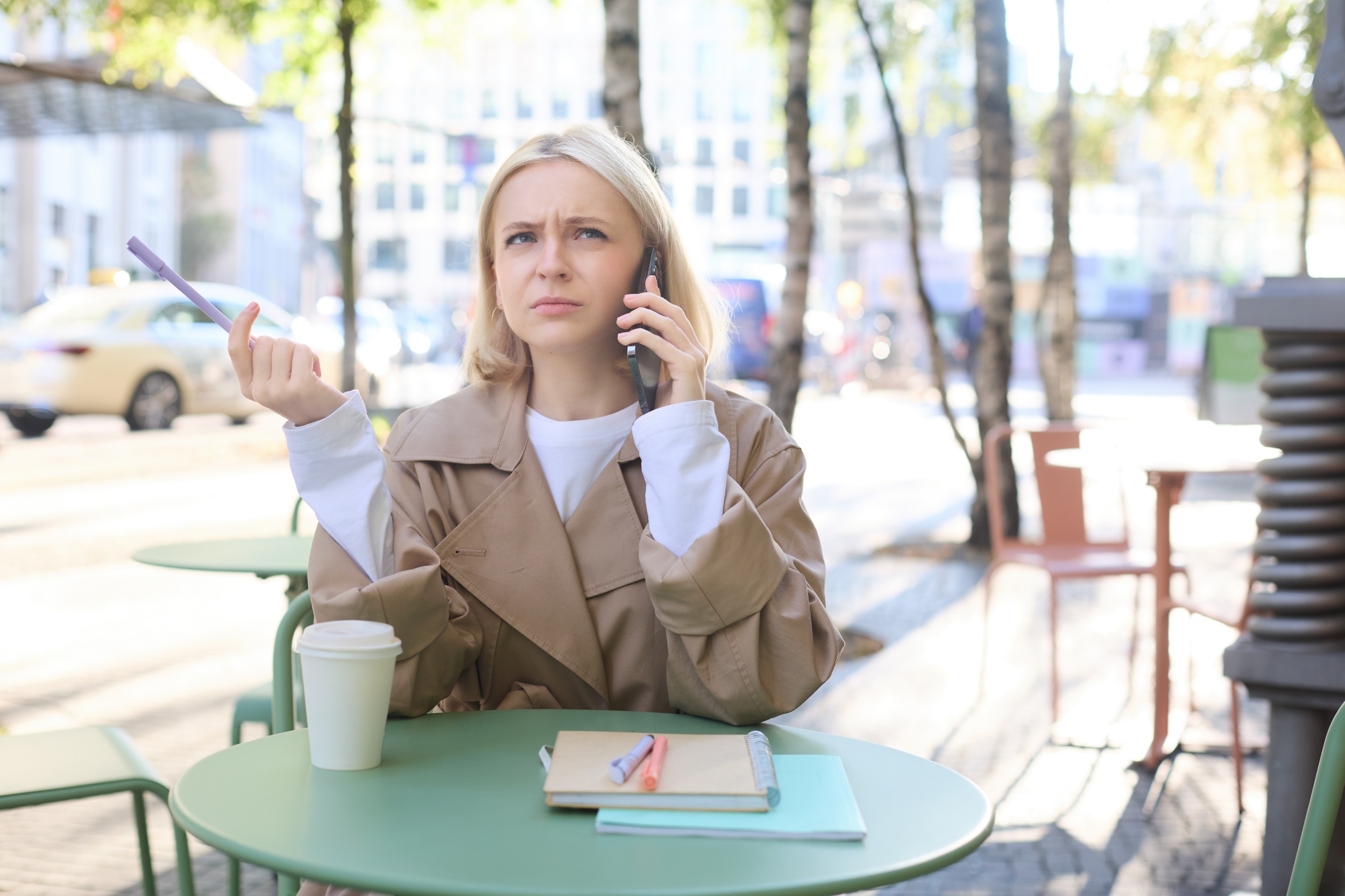 1 portrait-woman-student-doing-homework-outdoors-cafe-holding-pen-frowning-while-calling-someone.jpg